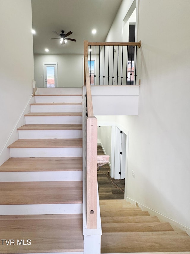 stairway featuring ceiling fan and hardwood / wood-style floors