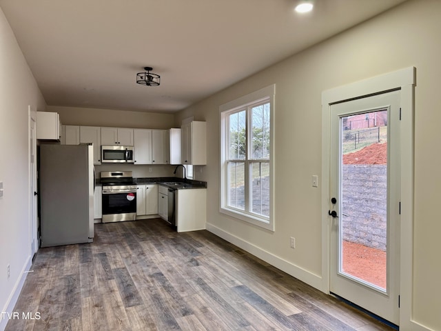 kitchen with wood-type flooring, appliances with stainless steel finishes, sink, and white cabinets