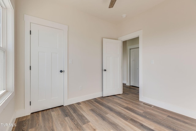 unfurnished bedroom with visible vents, baseboards, and wood finished floors