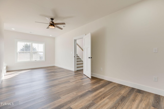 unfurnished room with ceiling fan, stairs, baseboards, and wood finished floors