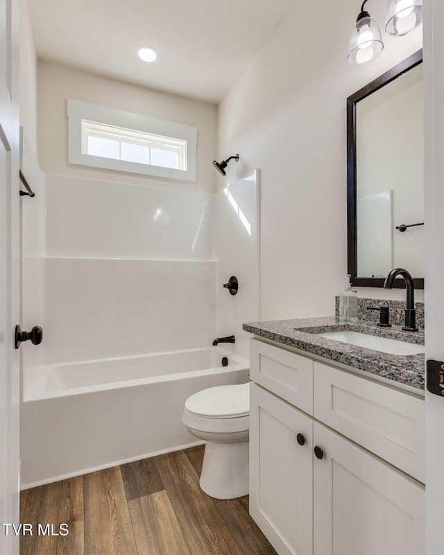 bathroom with vanity, toilet, wood finished floors, and shower / bathtub combination