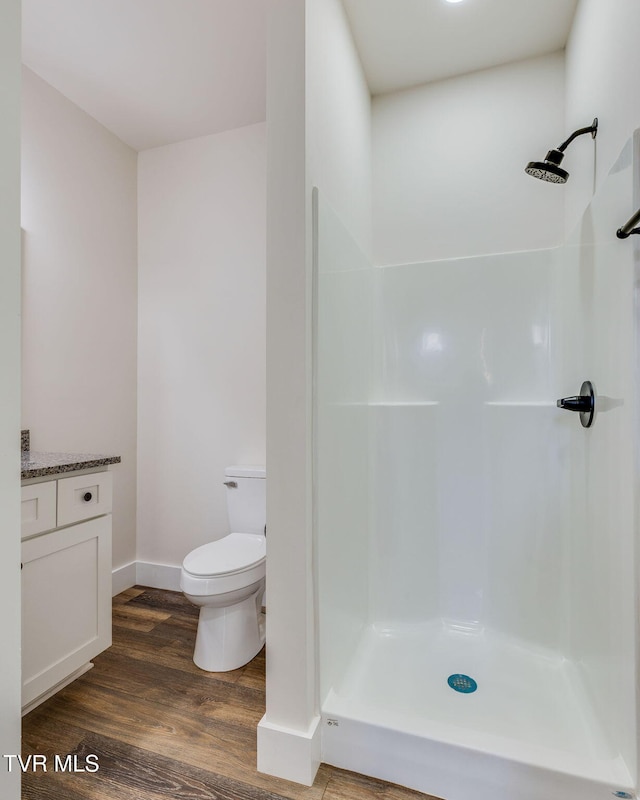 full bathroom featuring vanity, wood finished floors, baseboards, a shower, and toilet