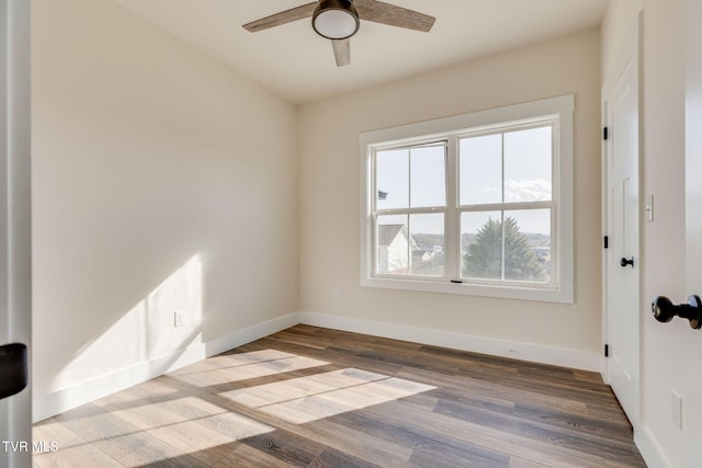 empty room with a ceiling fan, wood finished floors, and baseboards