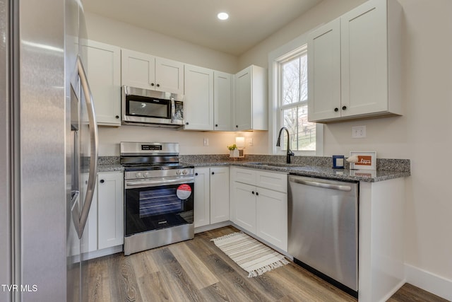 kitchen featuring a sink, stainless steel appliances, light wood-style flooring, and white cabinets