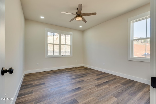 empty room featuring a healthy amount of sunlight, baseboards, and dark wood-style flooring