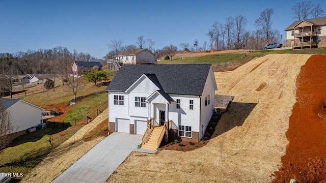 view of front of home with driveway, roof with shingles, an attached garage, brick siding, and a residential view