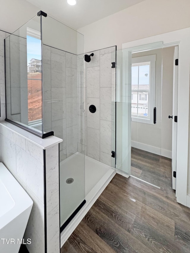 full bathroom featuring a shower stall, a soaking tub, wood finished floors, and baseboards