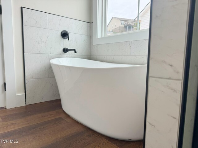 bathroom with a freestanding bath and wood finished floors