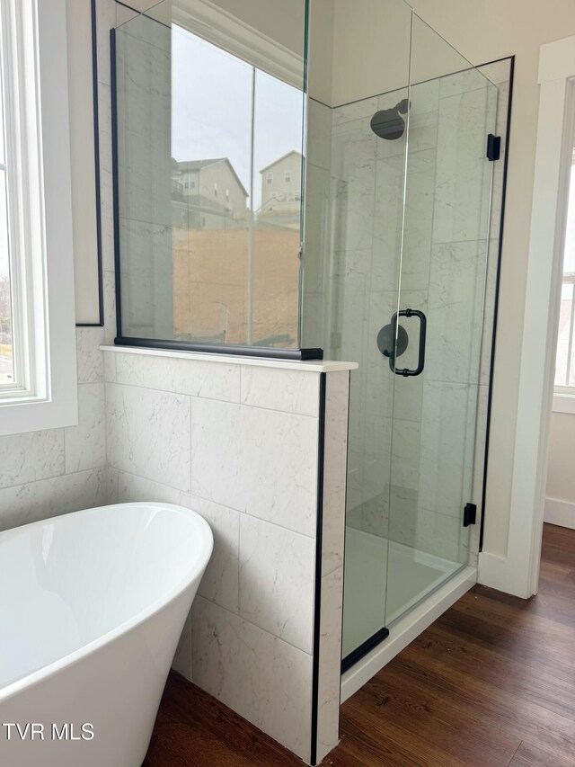 full bathroom with a stall shower, wood finished floors, and a freestanding tub