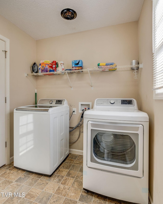 clothes washing area featuring washer and dryer and a textured ceiling