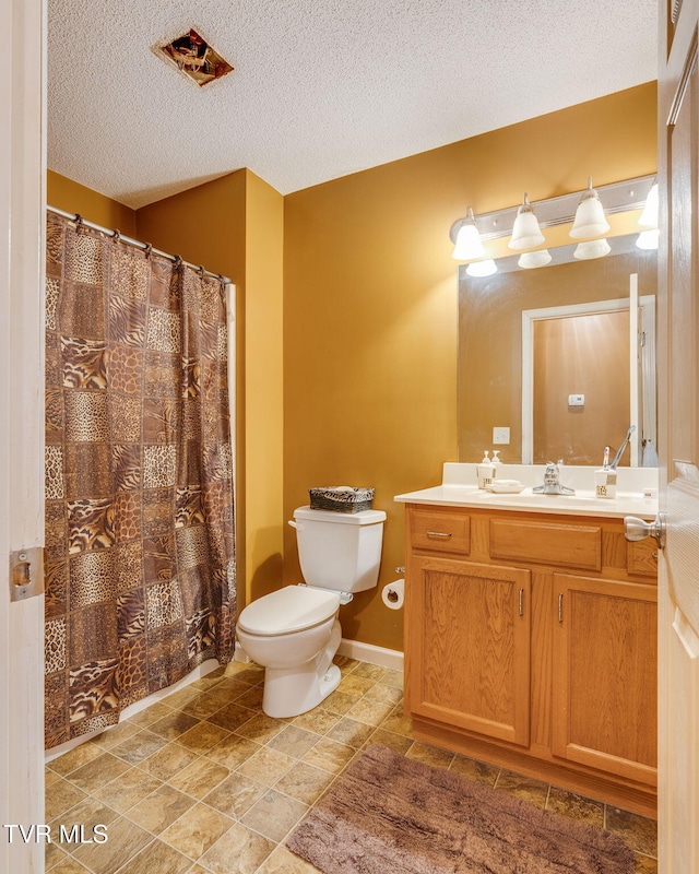 bathroom featuring a textured ceiling, toilet, and vanity