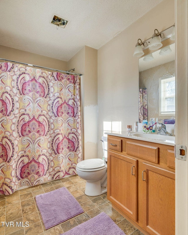 bathroom with a textured ceiling, toilet, and vanity