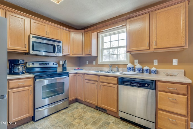 kitchen with sink, a textured ceiling, and stainless steel appliances