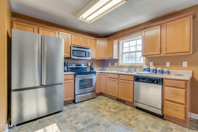 kitchen with sink, a textured ceiling, and appliances with stainless steel finishes