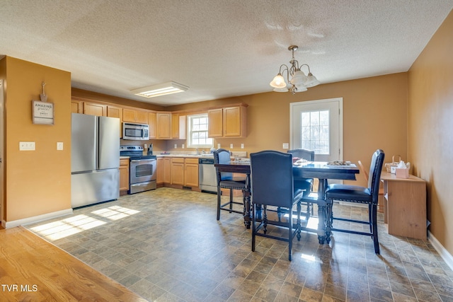 kitchen featuring stainless steel appliances, a healthy amount of sunlight, a chandelier, and hanging light fixtures