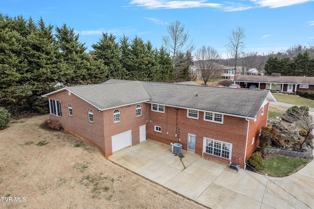 rear view of house featuring central AC unit and a garage