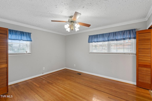 empty room with hardwood / wood-style flooring, a textured ceiling, crown molding, and ceiling fan