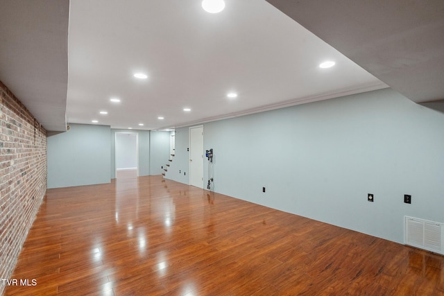 basement featuring light hardwood / wood-style floors and brick wall