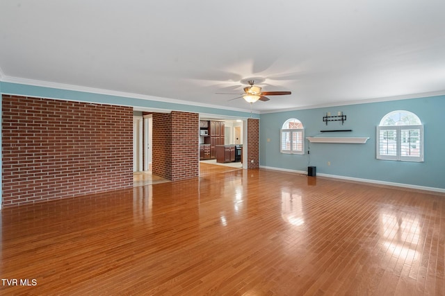 unfurnished living room featuring brick wall, crown molding, and a healthy amount of sunlight