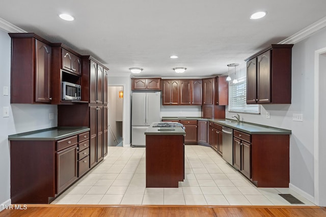 kitchen featuring hanging light fixtures, ornamental molding, stainless steel appliances, and a center island