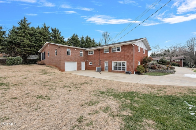 rear view of house featuring a lawn, central air condition unit, a patio, and a garage