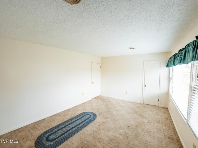 empty room featuring light colored carpet and a textured ceiling