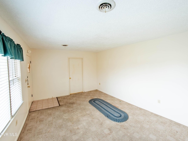 spare room with light carpet and a textured ceiling