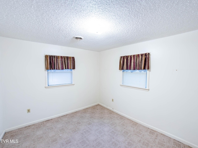 spare room featuring a textured ceiling and light colored carpet