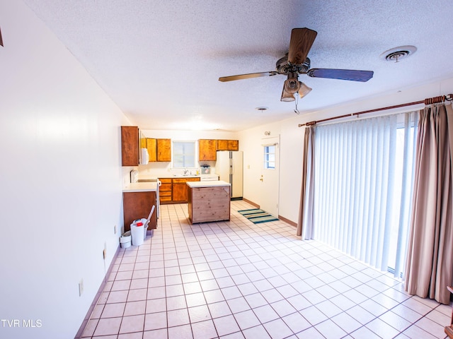 kitchen featuring light tile patterned floors, white appliances, and a textured ceiling