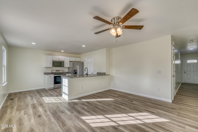 kitchen featuring light stone countertops, white cabinets, appliances with stainless steel finishes, sink, and kitchen peninsula