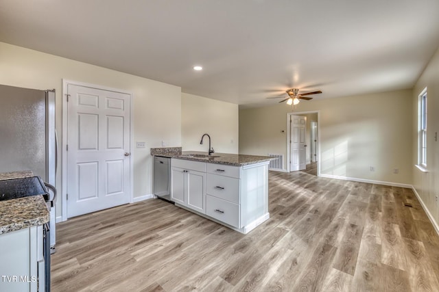 kitchen with white cabinets, kitchen peninsula, light stone countertops, and sink