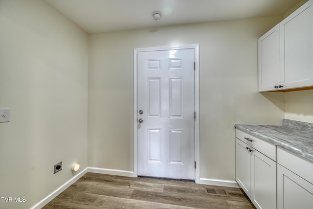 laundry area featuring cabinets, light hardwood / wood-style floors, and hookup for an electric dryer