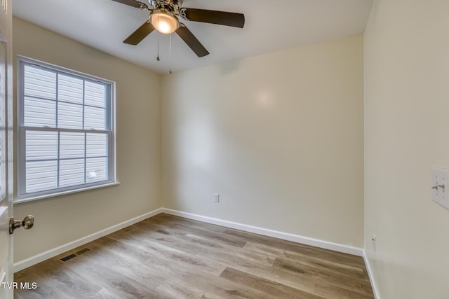 spare room featuring ceiling fan, a wealth of natural light, and light hardwood / wood-style flooring