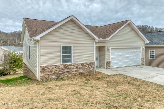 ranch-style home with stone siding, an attached garage, and a shingled roof