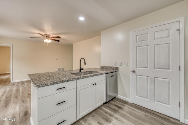 kitchen with white cabinetry, kitchen peninsula, dishwasher, light stone countertops, and sink