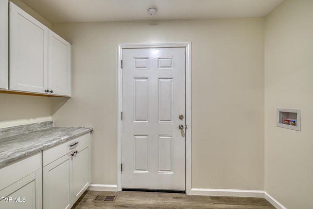 washroom featuring washer hookup, cabinets, and light hardwood / wood-style floors