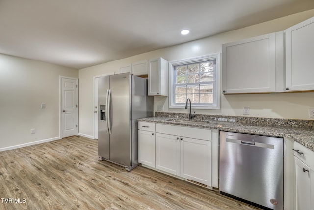 kitchen featuring stone counters, stainless steel appliances, white cabinetry, and sink