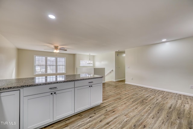 kitchen featuring ceiling fan, light wood-type flooring, stone countertops, and white cabinetry