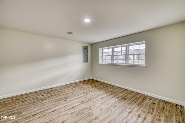 unfurnished room with electric panel and light hardwood / wood-style flooring