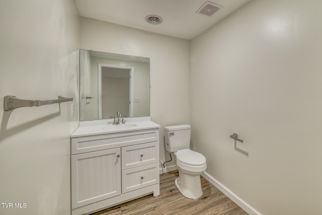 bathroom with toilet, vanity, and wood-type flooring