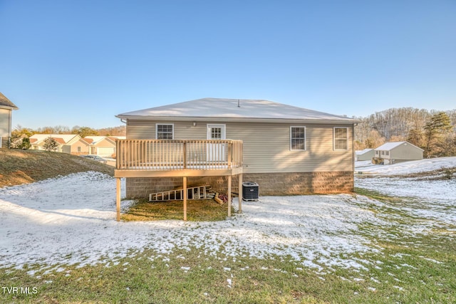 snow covered house with a deck and cooling unit