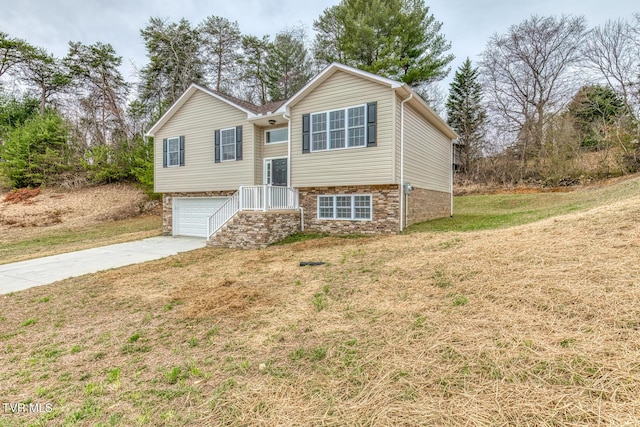 bi-level home with concrete driveway, a garage, and a front yard