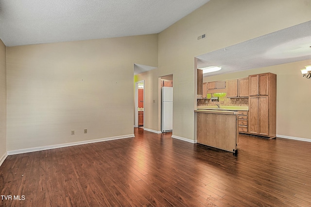 kitchen featuring backsplash, dark hardwood / wood-style floors, white fridge, high vaulted ceiling, and a chandelier