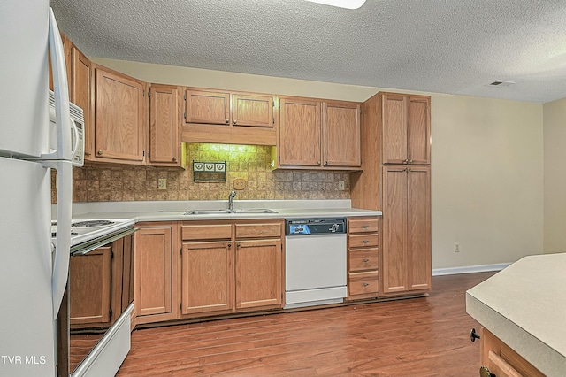 kitchen with light hardwood / wood-style floors, decorative backsplash, white appliances, a textured ceiling, and sink