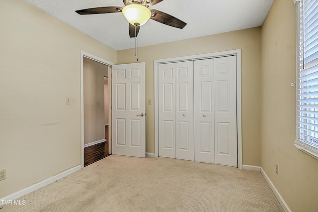 unfurnished bedroom featuring ceiling fan, a closet, and light colored carpet