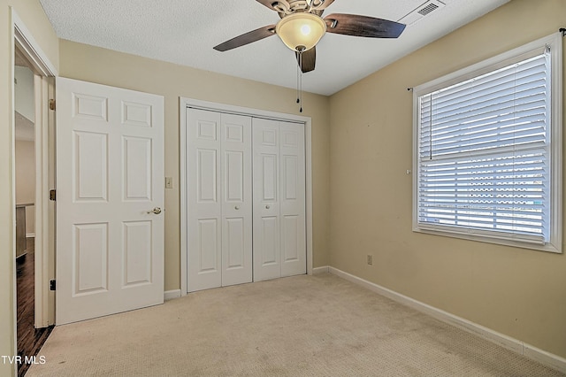 unfurnished bedroom featuring ceiling fan, a closet, and light colored carpet