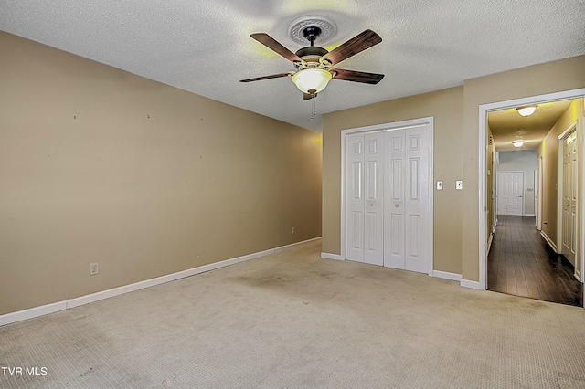 unfurnished bedroom featuring a textured ceiling, ceiling fan, carpet flooring, and a closet