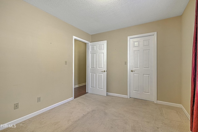 unfurnished bedroom featuring a textured ceiling and light colored carpet