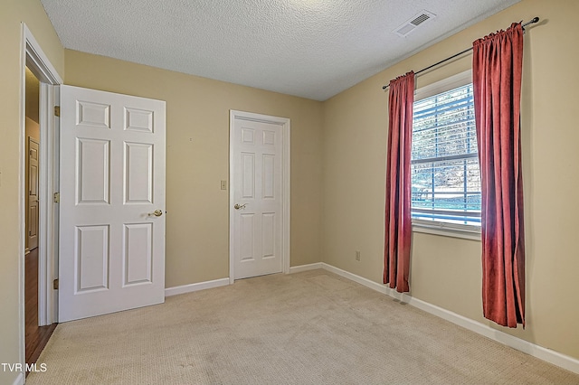 unfurnished bedroom with a textured ceiling and light carpet