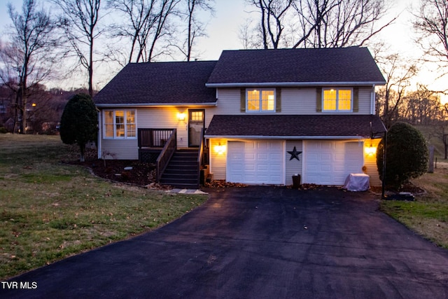 tri-level home with a shingled roof, driveway, an attached garage, and stairs